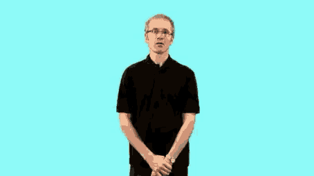 a man wearing glasses and a black shirt is standing with his arms outstretched .