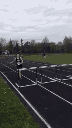 a man is jumping over hurdles on a track wearing number 142