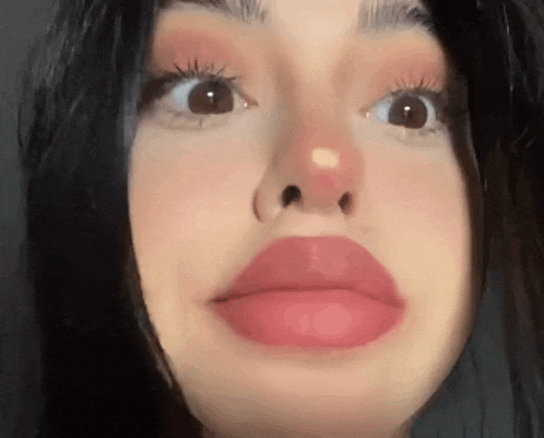 a close up of a woman 's face with red lips and a nose ring .