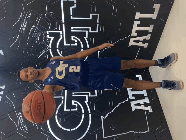 a man wearing a gt 2 jersey holds a basketball