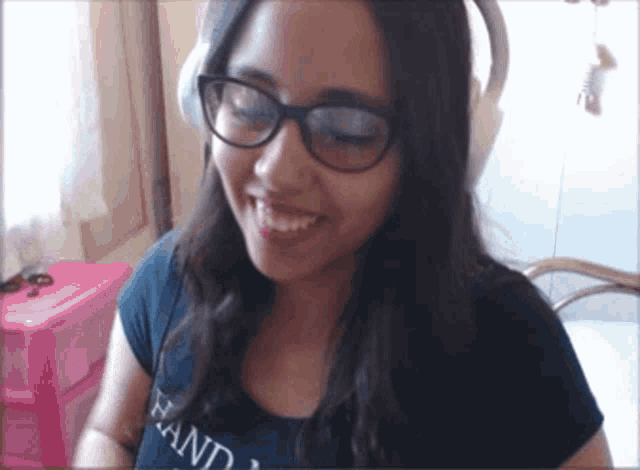 a woman wearing glasses and headphones has the word hand on her shirt