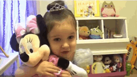 a little girl is holding a stuffed minnie mouse in her arms