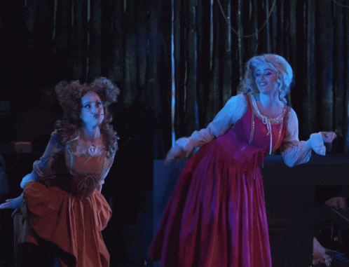 two women in costume are dancing on a stage