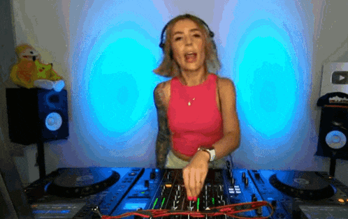 a woman in a pink top is playing music on a dj mixer