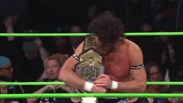 a man in a wrestling ring with a championship belt on his chest