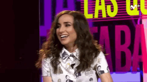 a woman is laughing in front of a sign that says m+