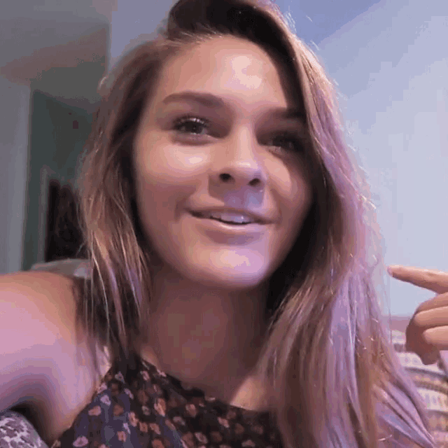 a woman with long hair is smiling and pointing at her hair