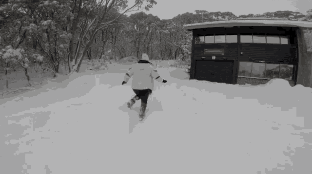 a person is running through a snowy area in front of a house .