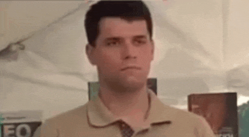 a man in a polo shirt and tie is standing in front of a tent .