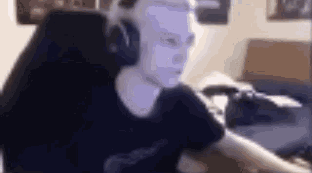 a man wearing headphones and a blue mask is sitting at a computer .