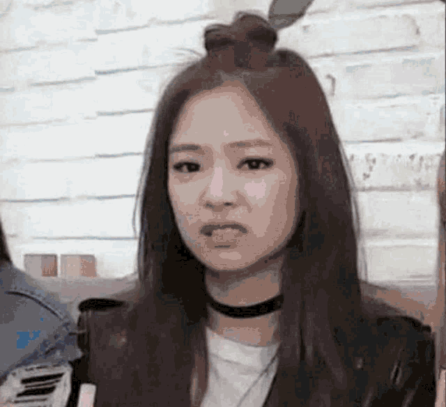 a woman with long hair is wearing a choker and a bun on her head .