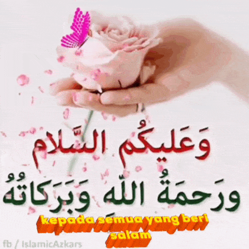 a person is holding a pink rose in their hand with arabic writing on it .