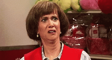 a woman in a red vest is making a funny face in front of a shelf with stuffed animals .
