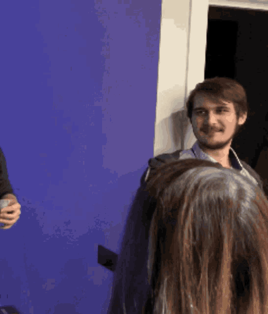 a man with a beard stands next to a woman with purple hair