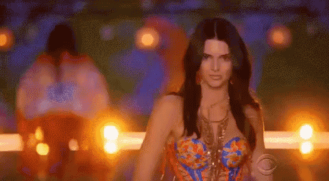 a woman in a blue and orange dress is walking down a runway .