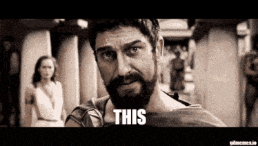 a man with a beard is standing in front of a woman and saying this .