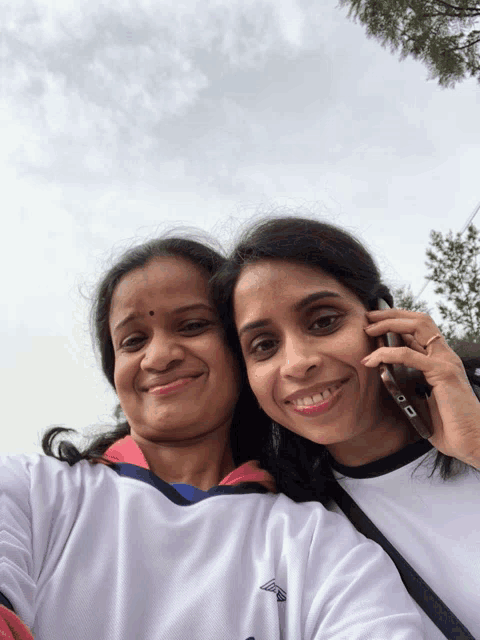 two women posing for a picture with one wearing a shirt that says reebok on it