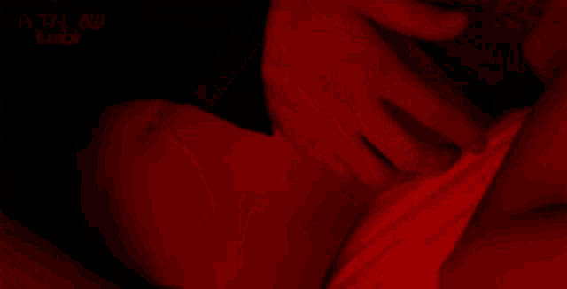 a close up of a woman 's face in a red light with her eyes closed .