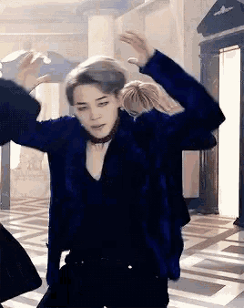 a man in a blue jacket is dancing with his arms in the air