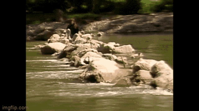 a woman is standing on a rock in a river