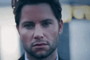 a close up of a man 's face with a beard wearing a suit and tie .