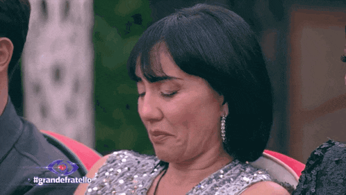 a woman is crying in front of a sign that says grandefratello on it