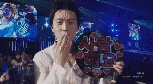 a man is blowing a kiss while holding a fan in his hand .