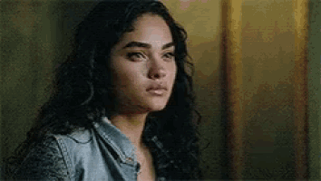 a close up of a woman 's face with curly hair and a denim shirt .