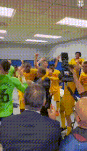 a group of soccer players are celebrating in a locker room with a cameraman