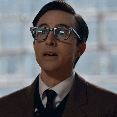 a close up of a man wearing glasses and a suit and tie