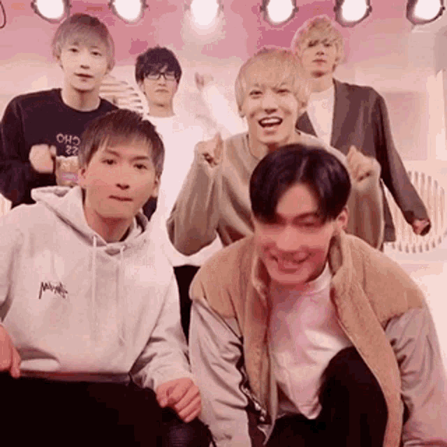 a group of young men are standing next to each other on a stage and laughing .