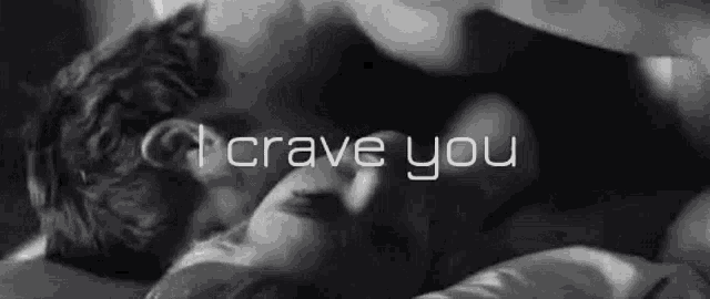 a black and white photo of a couple kissing in bed with the words `` i crave you '' written above them .