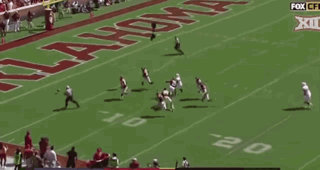 a football player in a red uniform with the number 8 on his helmet is being tackled by another player .