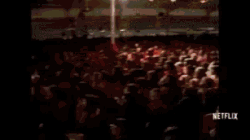 a large group of people in red robes are sitting in a circle in front of a netflix logo .
