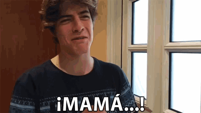 a young man is standing in front of a window and says " mama "