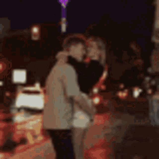 a blurry picture of a man and woman kissing on a city street .