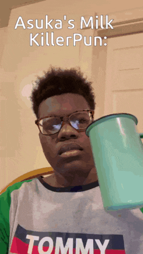 a young man wearing a tommy shirt holds a cup