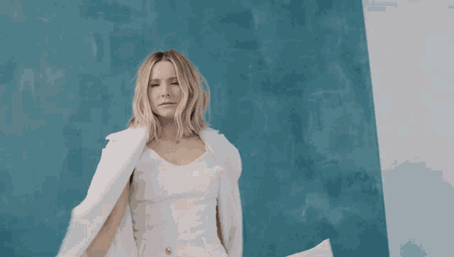 a woman wearing a white jacket and a white tank top