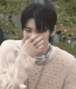 a man is covering his mouth with his hand while laughing .