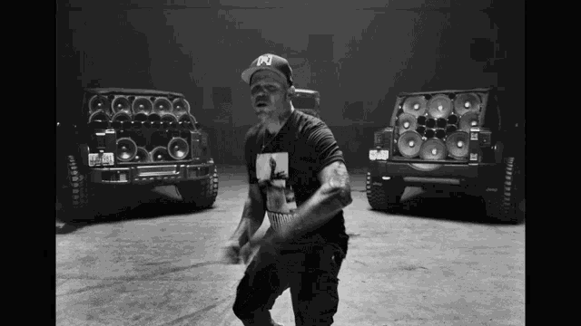 a man wearing a hat with the letter p on it is dancing in front of two jeep speakers