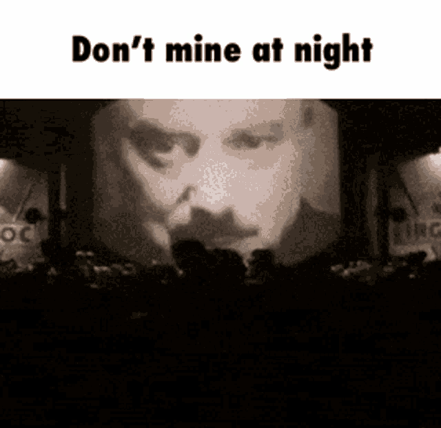 a man 's face is projected on a large screen with the words " do n't mine at night "