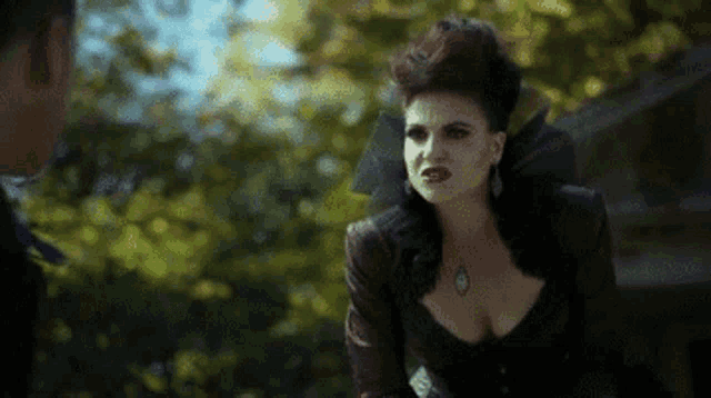 a woman in a very revealing dress is standing next to a man in a park .