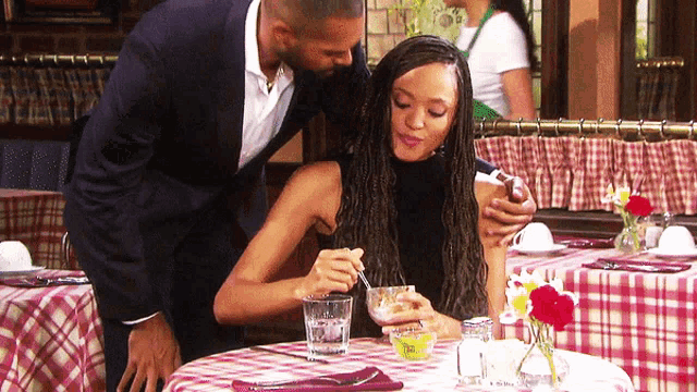 a man and a woman sit at a table with a plaid table cloth