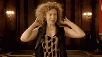 a woman with curly hair is wearing a black vest and a leopard print dress .