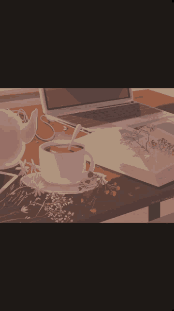 a cup of tea sits on a table next to a laptop and a book