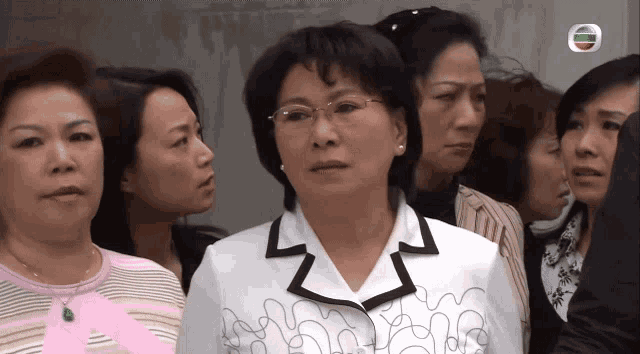 a woman wearing glasses stands in a crowd of people
