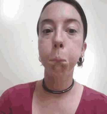 a woman wearing a choker necklace and earrings is making a face .