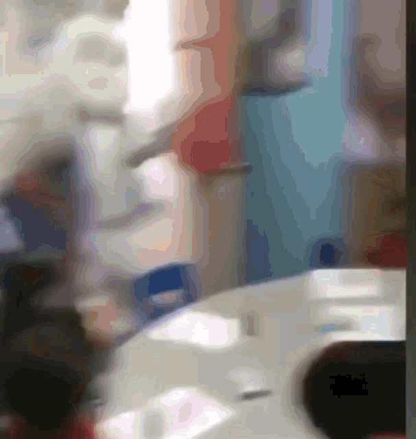 a blurry picture of people sitting at a table with a blue wall in the background