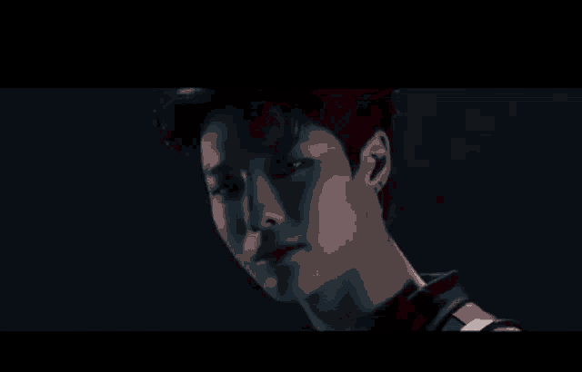 a close up of a young man 's face in a dark room with a black background .