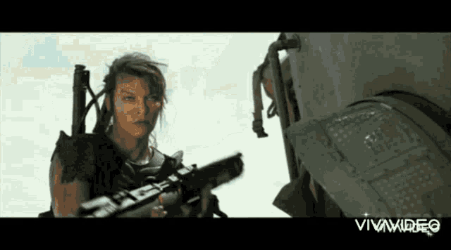 a woman is holding a gun in front of a machine and the words vivavideo are on the bottom